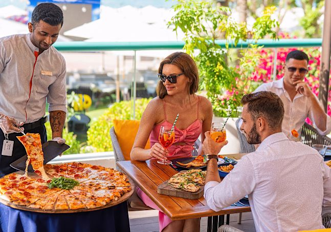 Сервьор сервира пица на семейство във Vero Restaurant