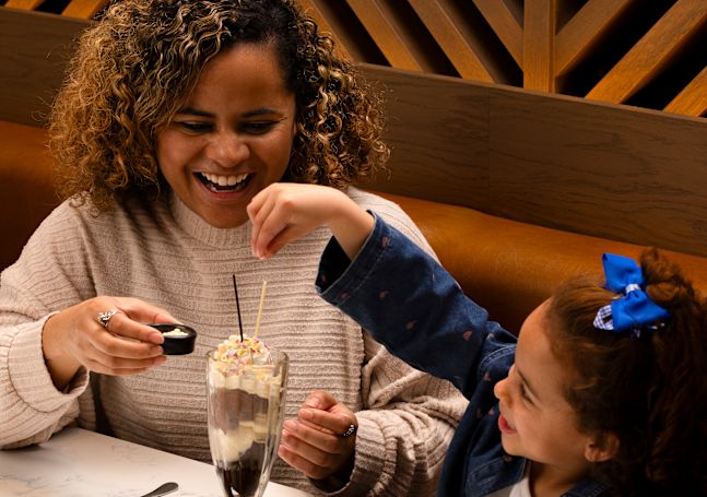 Mother and Daughter Enjoying Ice Cream in a Restaurant