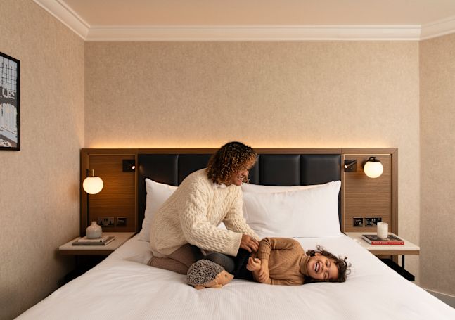 Mother and Daughter Playing on a Guest Room Bed