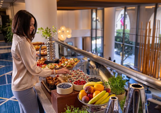 A woman is selecting foods at the breakfast buffet