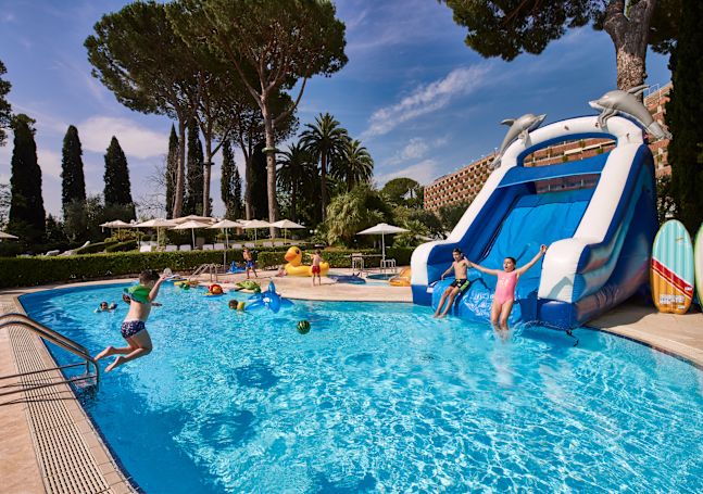 Kids swimming in pool and playing on large inflatable slide