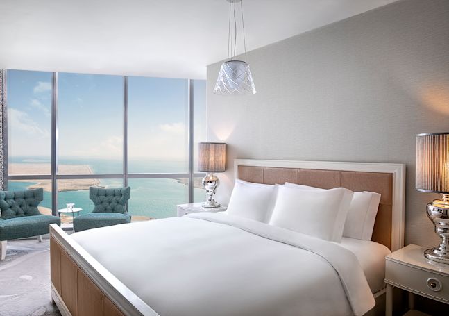 Grand lit et coin détente d'une suite Tower avec vue sur la mer