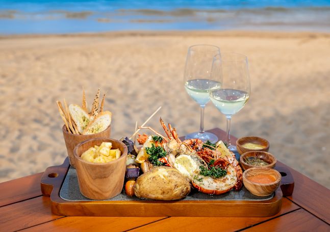 Seafood Dish and Drinks on a Table with Beach View