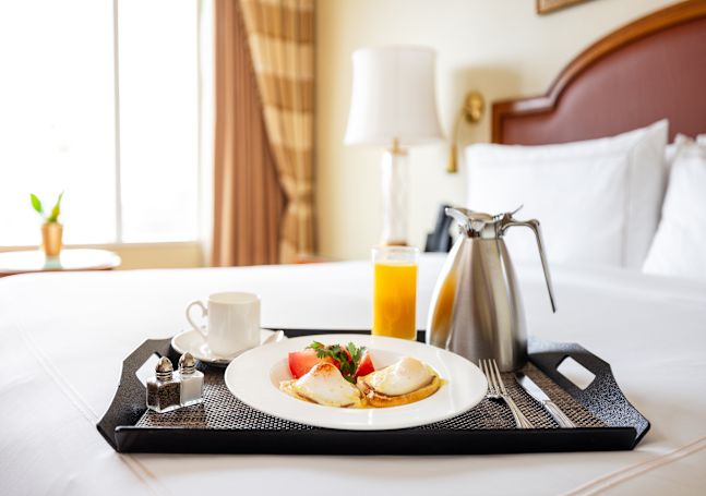 Bed with room service tray, orange juide and food