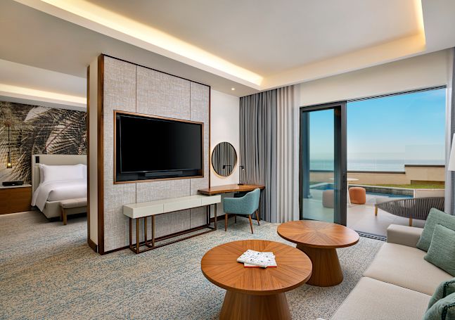 Suíte com um quarto, área de lounge com TV na parede, mesa de trabalho e pátio ao ar livre