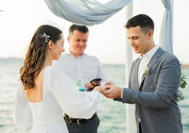 Beachfront wedding ceremony with bride, groom, and minister