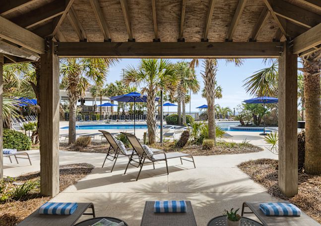 Beautiful outdoor cabana area featuring ample seating for guests and view of pool.