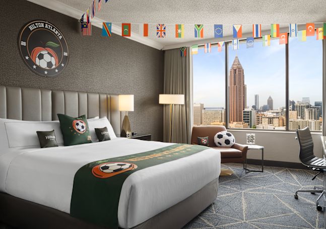 Large Bed, Seating Area and Desk in a Soccer Theme Suite with City View