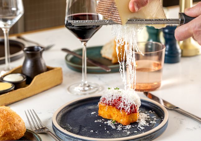 plated food dish on table with cheese being grated