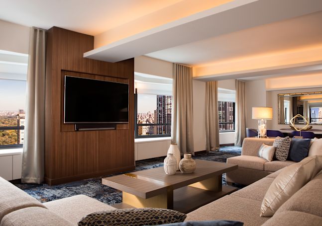 Suite living area with comfortable seating, wall mounted TV and views over the city