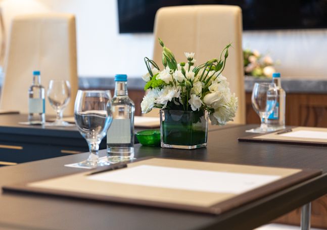 Closeup of desk jotter and glass of water in meeting room