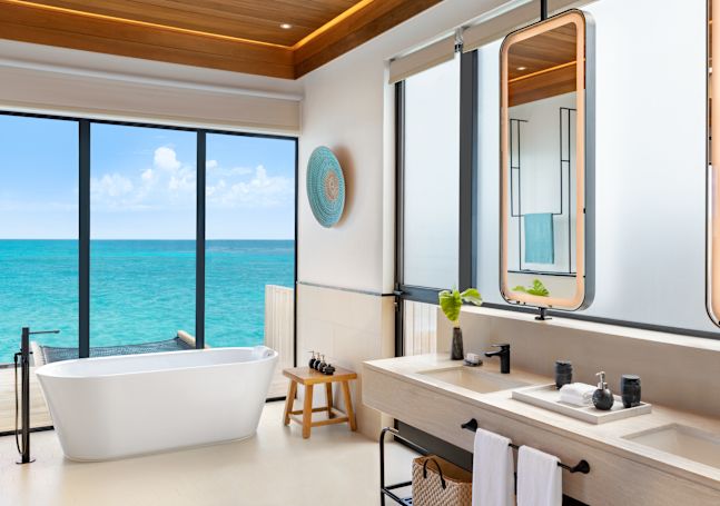 Overwater pool villa bathroom with tub and two sinks