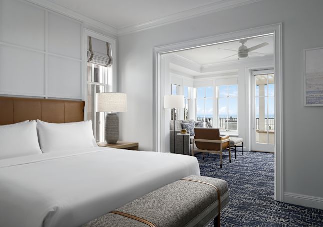 Groot bed in een kamer met zitgedeelte en uitzicht op het strand
