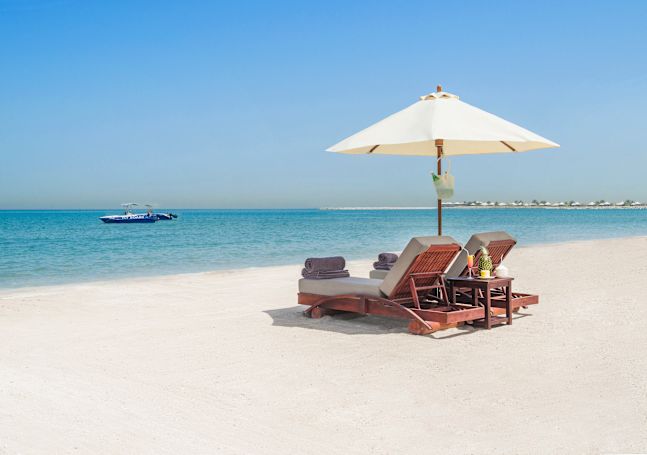 A couple of sun loungers sitting on a sandy beach