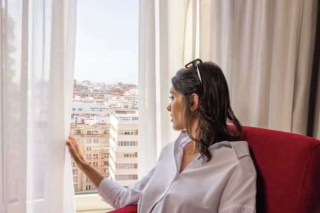 Mujeres sentadas en una silla cómoda mirando desde la ventana de la habitación
