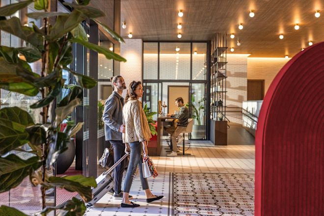 Hombre y mujer caminando por la entrada principal al lobby con equipaje