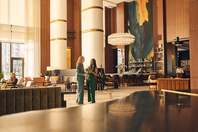Two women standing in spacious lobby area with bartender behind