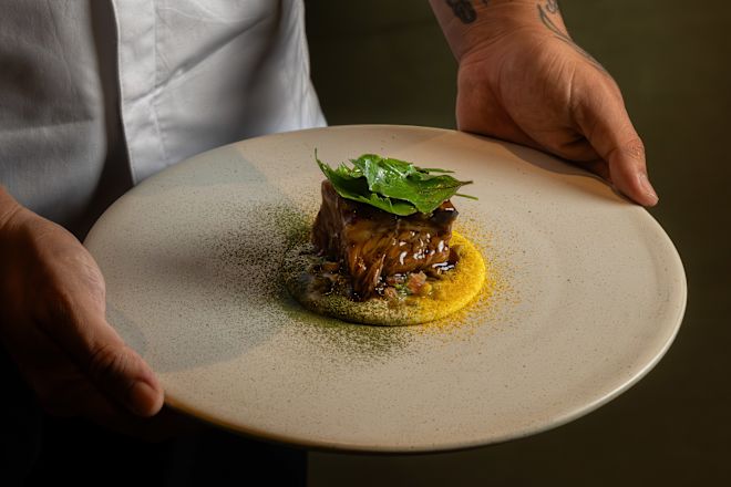 Chefkoch hält einen Teller mit einem einzigartigen Gericht im Restaurant "Autor"