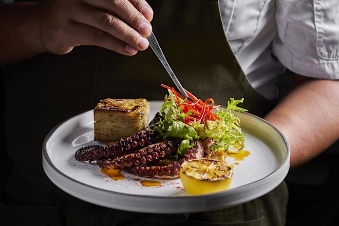 Le chef ajoute ses dernières touches à une assiette avec pieuvre et légumes au restaurant Maratea