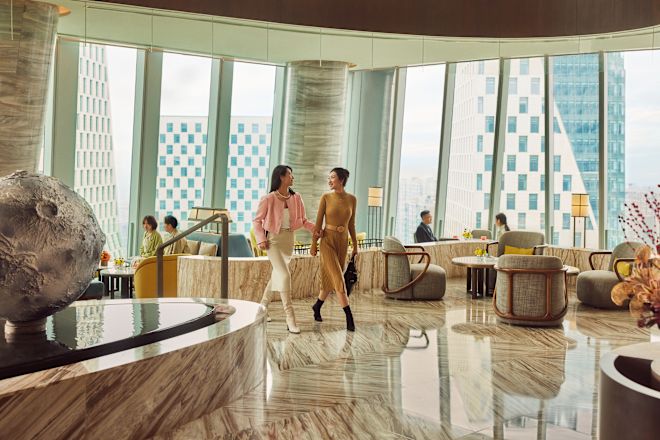 広々したロビーエリアを歩く2人の女性、植物が正面に