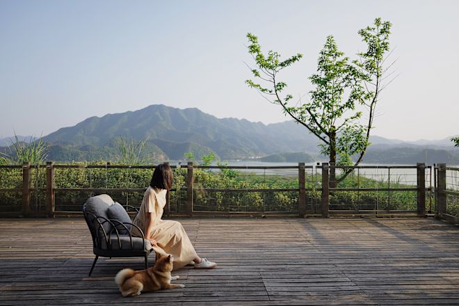 Woman with dog looking out over lake from deck