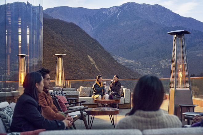 Sekelompok orang di area duduk luar ruangan dengan pemandangan gunung