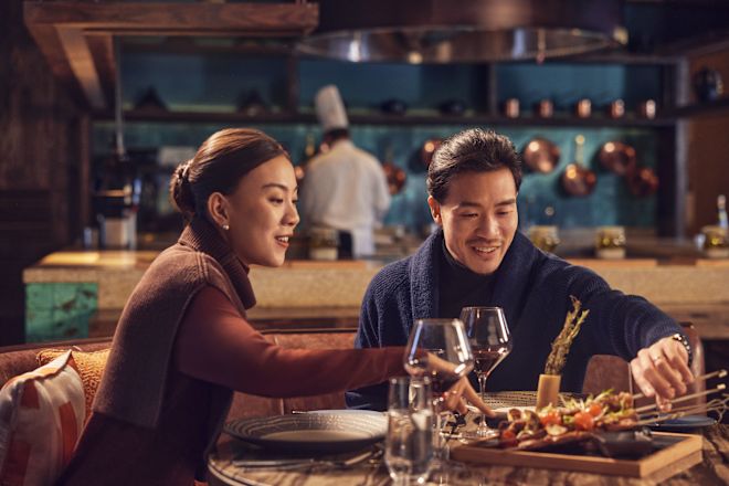 Pria dan wanita duduk di meja restoran dengan piring makanan