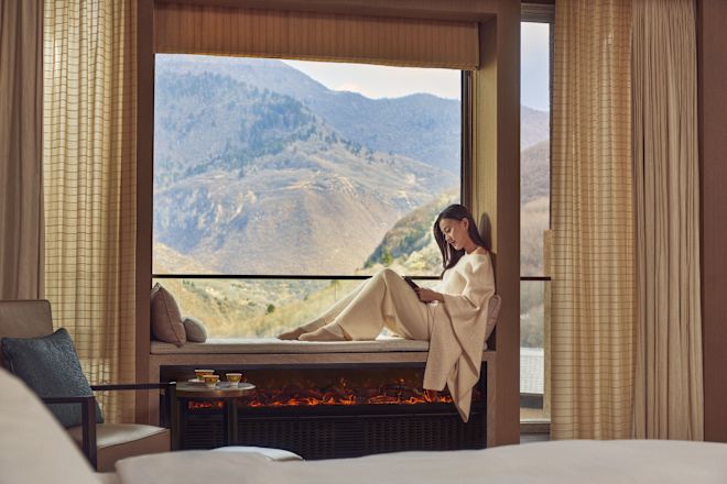 Wanita bersantai di ambang jendela dengan pemandangan gunung