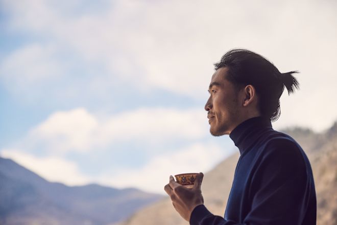 Pria berdiri di luar dengan kaca mengagumi pemandangan gunung