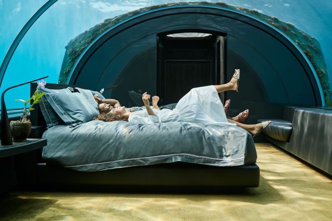 Man and woman relaxing on bed in underwater guest room
