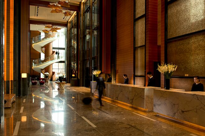 Spacious lobby area at Conrad Seoul, featuring high ceilings and marble floors. A spiral staircase is in the background.