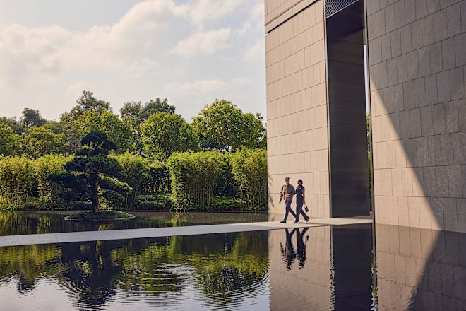 Man and woman walking along concrete path across body of water