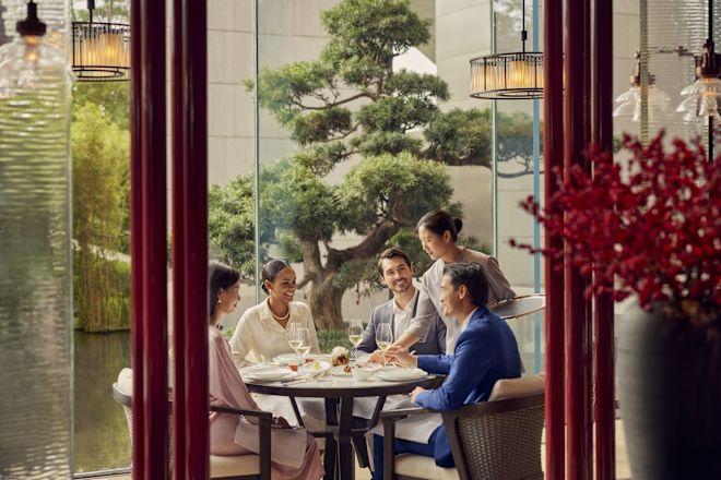 Group of people eating at table as waiting staff places food