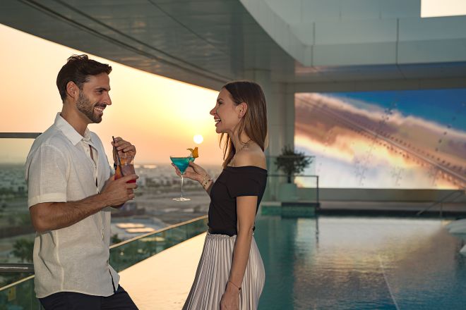 Man and woman with drinks near balcony at sunset alternate angle