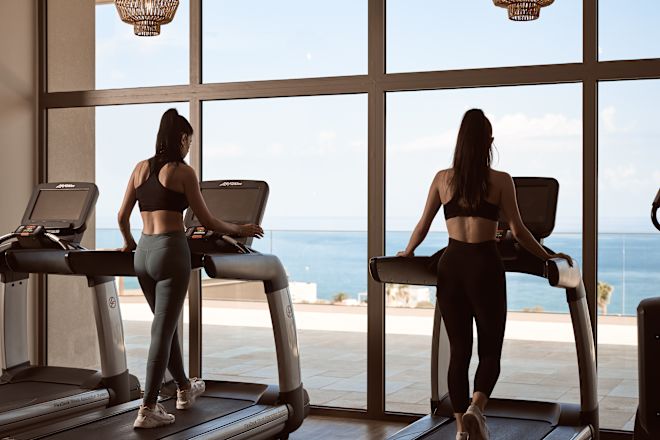 Women on Treadmills in Fitness Center with Beach View