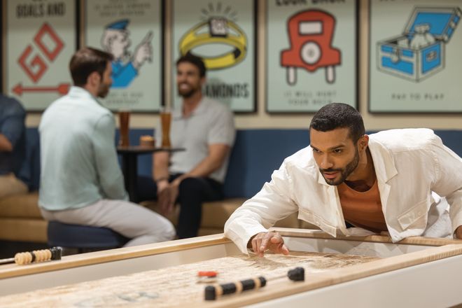 Man Playing Shuffleboard at Dive Bar