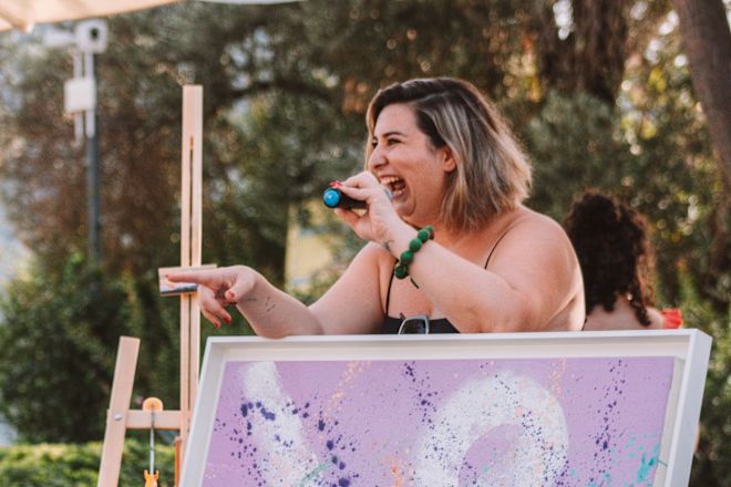 Woman on microphone behind piece of art