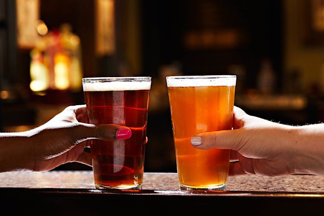 Tampak dari dekat dua orang yang berdering-dering sambil memegang gelas bir