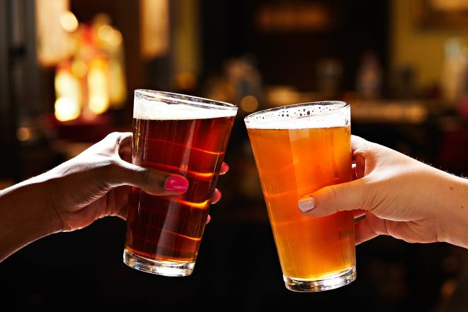 Close up of two people clinking glasses of beer