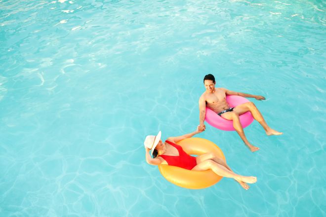 Man and woman relaxing in pool, on rubber rings