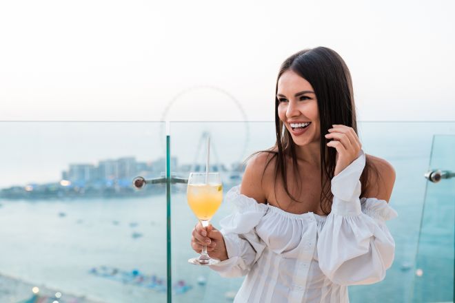 Woman holding a drink on the Pure Sky Lounge terrace