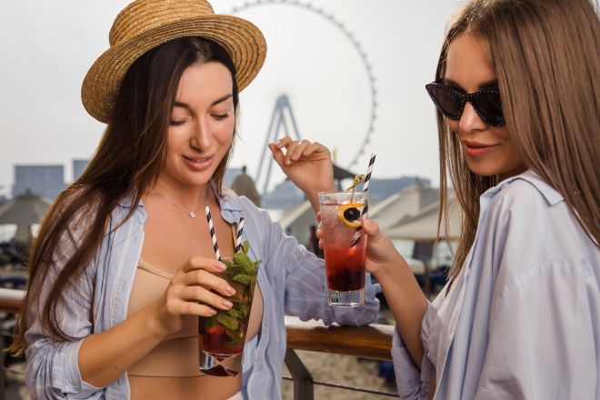 Two girls on the beach having cocktails