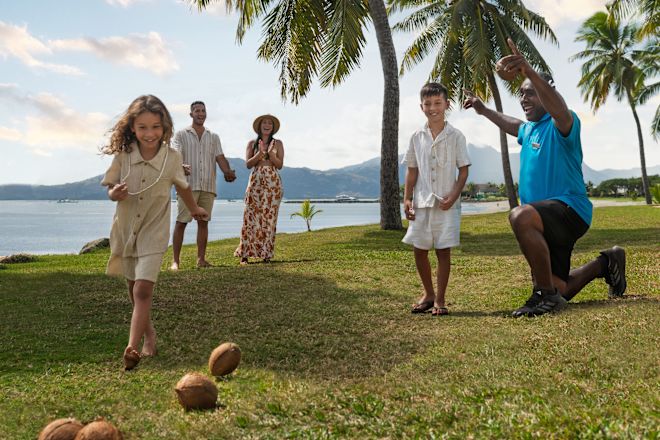 Eine Kokosnuss-Bowling für die ganze Familie auf dem Rasen vor dem Strand.