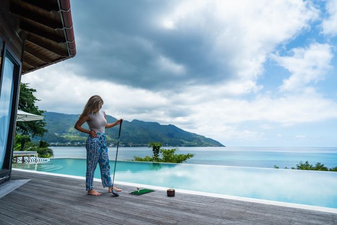 Người phụ nữ đứng trên sân thượng với hồ bơi vô cực và tầm nhìn ra đại dương