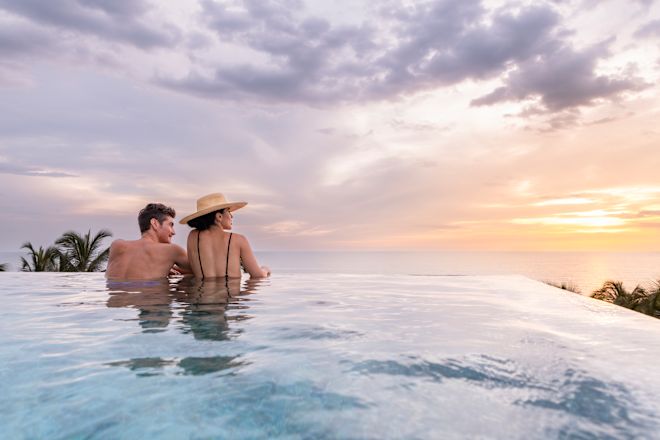 Man and woman relaxing in pool with sea view