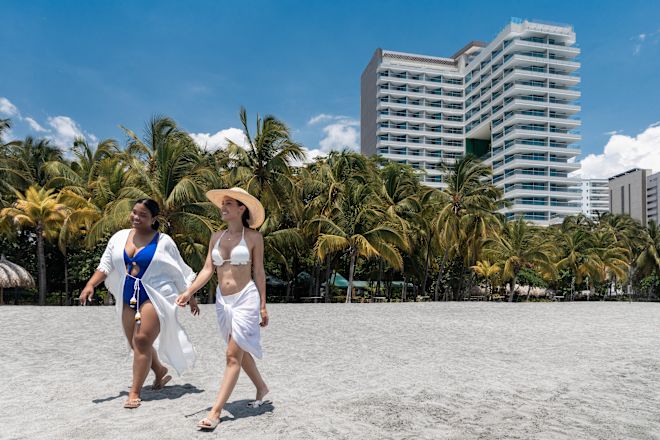 Two women walking along beach, with hotel in background
