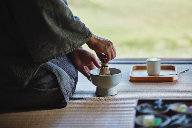 Person kneeling on floor preparing tea