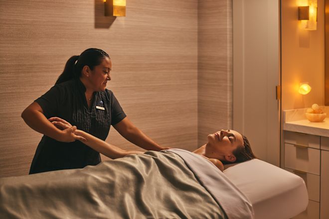 Woman in spa treatment room receiving massage from masseuse