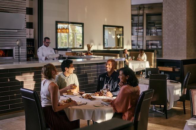 Group of people sitting in restaurant, with staff member behind bar