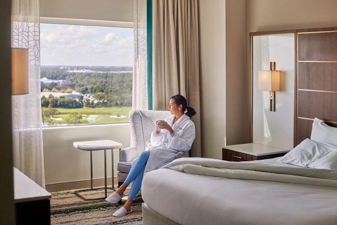 Woman relaxing in guest room seating area holding drink
